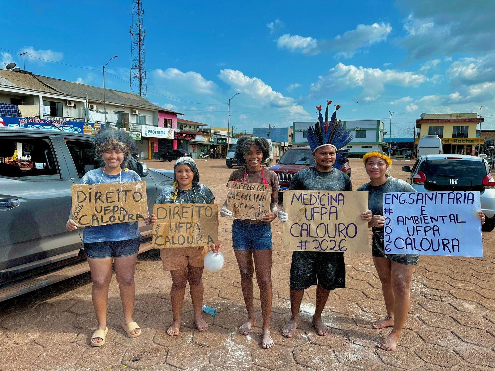 Cinco calouros comemoram segurando placas de aprovação dos cursos da UFPA