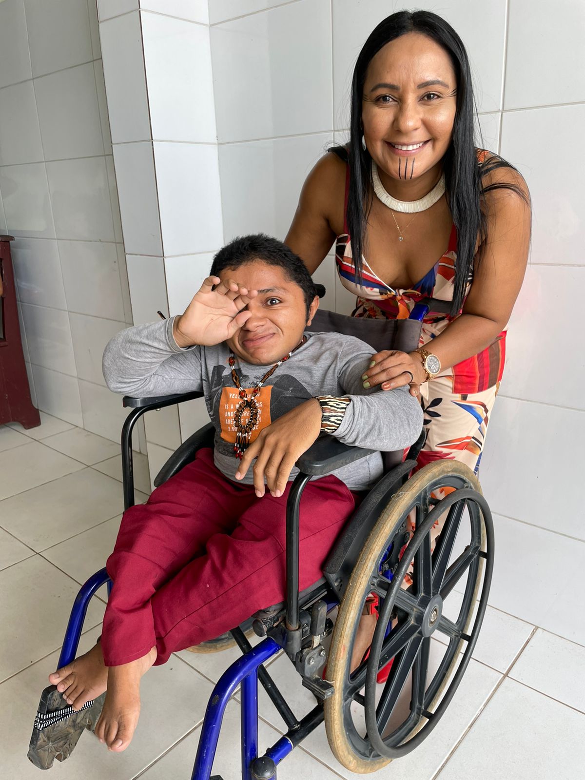 Titular da SEpi ao lado de paciente beneficiado por cadeira de rodas.